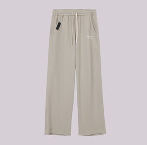 White London Clothing beige relaxed fit trousers with drawstring waist and subtle logo detail.