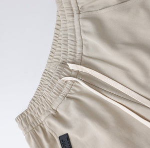White London Clothing beige relaxed fit trousers with drawstring and elastic waistband, made from durable fabric.