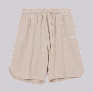 White London Clothing beige oversized textured waffle knit cotton shorts with drawstring waist and logo accent.