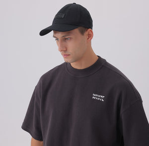 White London Clothing black cotton twill baseball cap with tonal embroidered logo patch and pre-curved brim, worn by a man.