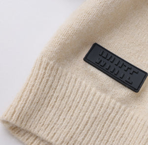 White London Clothing taupe knitted sweater with a black logo patch. Soft yarn, timeless silhouette for women.