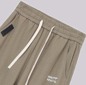 White London Clothing beige casual fit trousers with drawstring and logo detail.