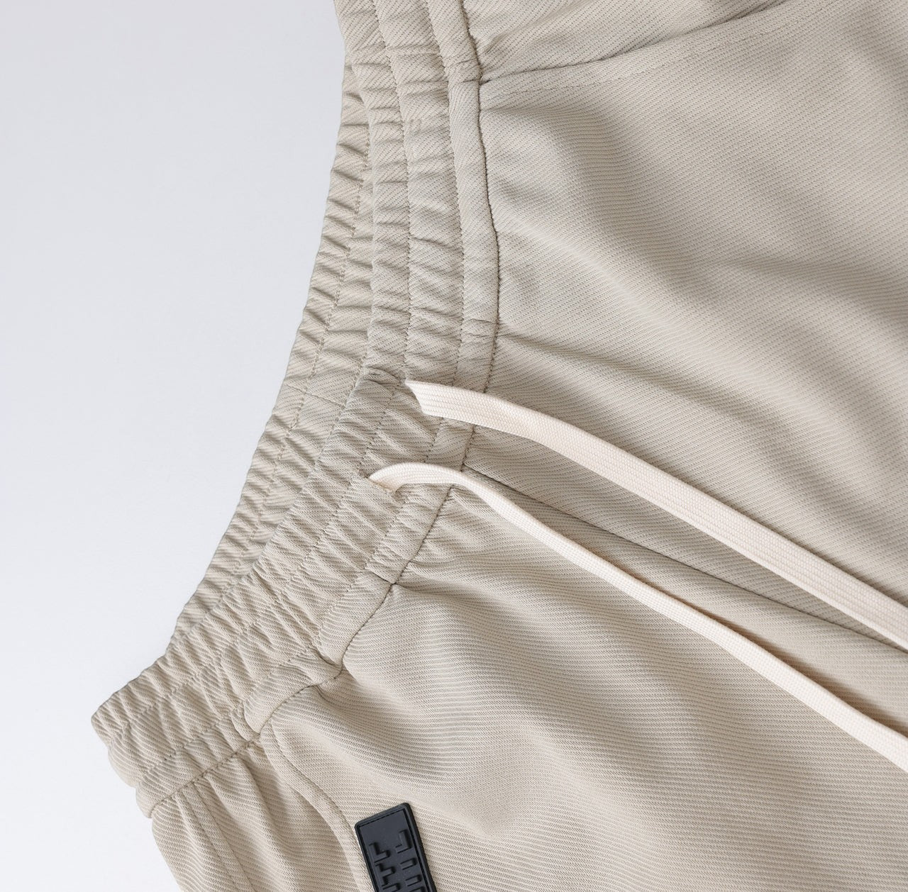 White London Clothing beige relaxed fit trousers with drawstring and elastic waistband, made from durable fabric.