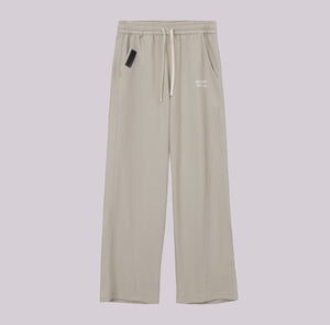 White London Clothing beige relaxed fit trousers with drawstring waist and subtle logo detail.