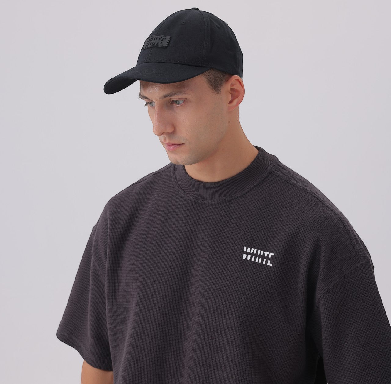 White London Clothing black cotton twill baseball cap with tonal embroidered logo patch and pre-curved brim, worn by a man.