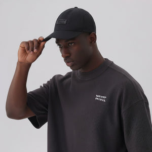 White London Clothing black cotton twill baseball cap with tonal embroidered logo patch and adjustable strap.