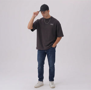 White London Clothing black cotton twill baseball cap with tonal embroidered patch and pre-curved brim, worn by a man.