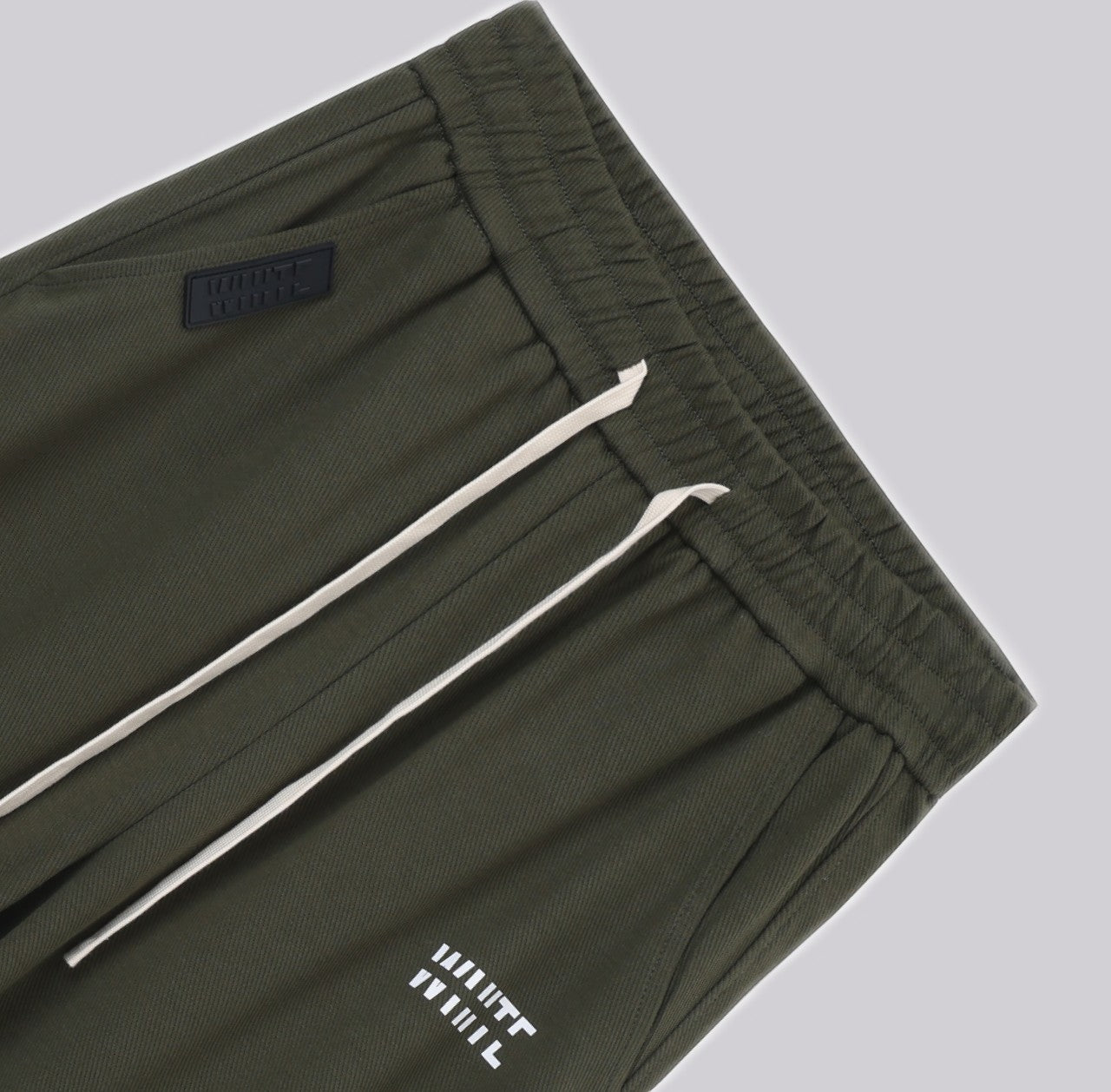 White London Clothing dark green casual fit trousers with drawstring and logo detail.