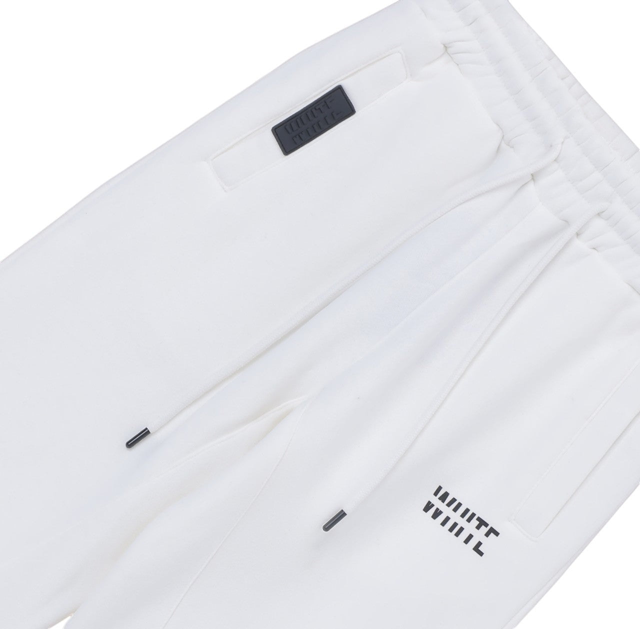 White London Clothing white cotton jersey joggers with cropped length, drawstring waist, and embossed logo tag on pocket.