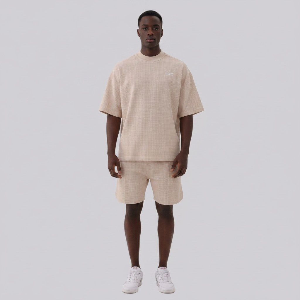 White London Clothing beige oversized textured shorts with elasticated waistband and subtle logo detail on left leg.