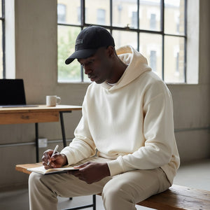White London Clothing black cotton twill baseball cap with tonal embroidered patch on front, worn by a man.