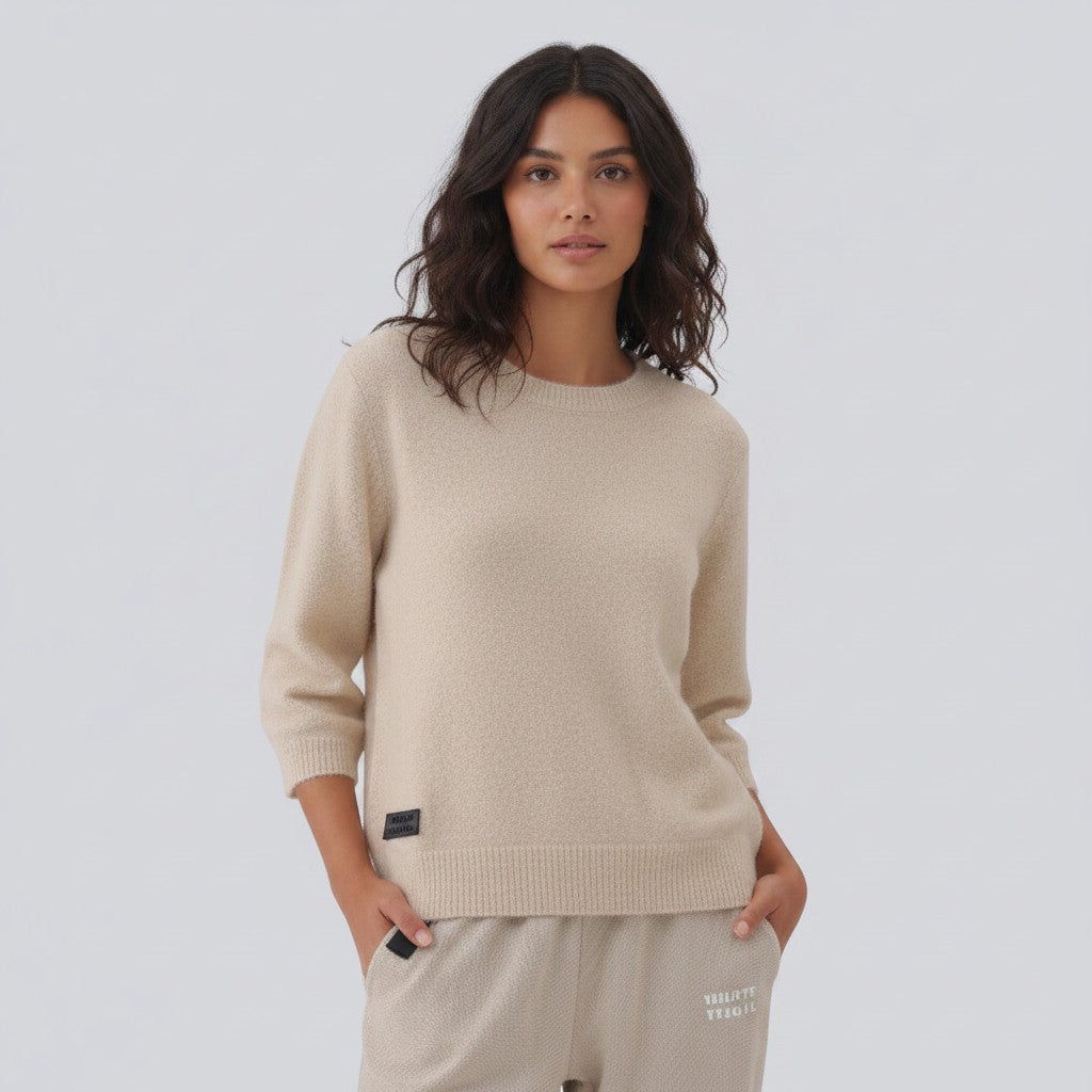 White London Clothing taupe knitted sweater with 3/4 sleeves and a crew neck, featuring a small black logo patch on the hem.